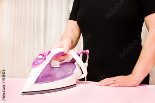 ironing clothes with steam iron at board