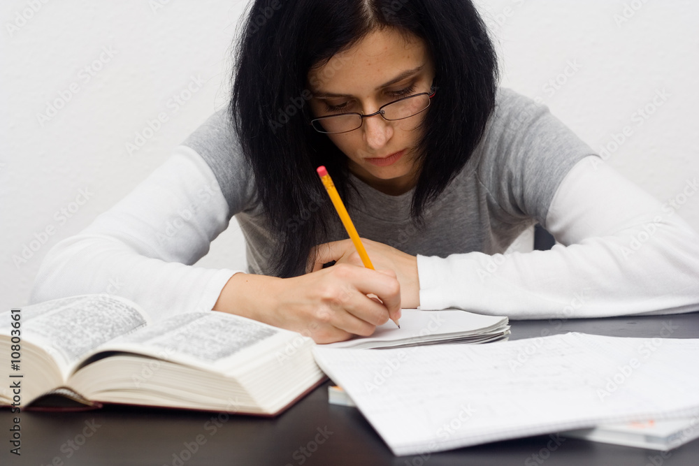 young caucasian woman sitting behind the desk and studying young caucasian woman sitting behind the desk and studying
