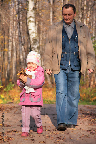 Grandfather with granddaughter walk in wood in autumn