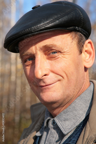 Portrait of elderly man in black hat in wood in autumn