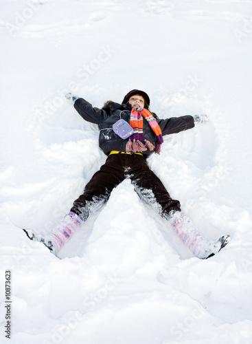 Winter child play lie in snow at sunny day