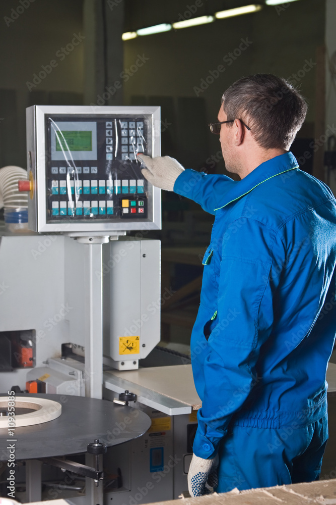 The worker presses buttons of the panel of the machine tool The worker presses buttons of the panel of the machine tool
