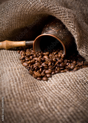 Cezve with freshly roasted coffee beans on sackcloth photo