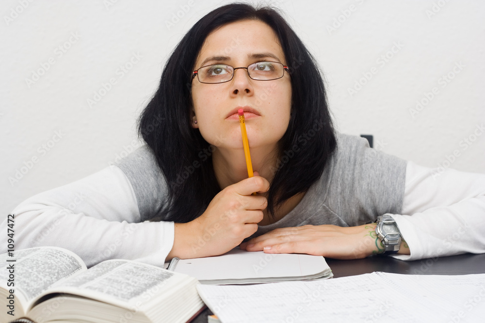 young caucasian woman sitting behind the desk and studying young caucasian woman sitting behind the desk and studying