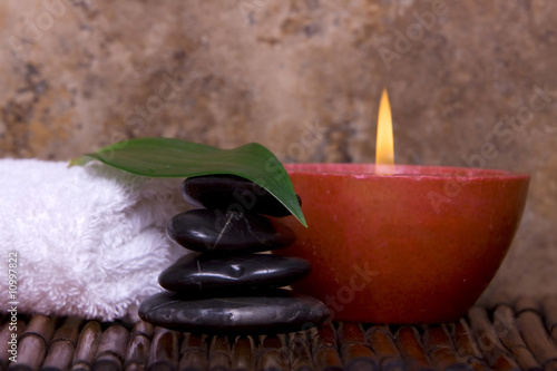 Balanced pebble rocks, candle, white towel set on bamboo