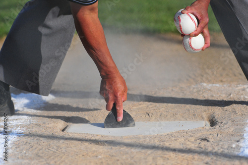 Umpire cleaning home plate.