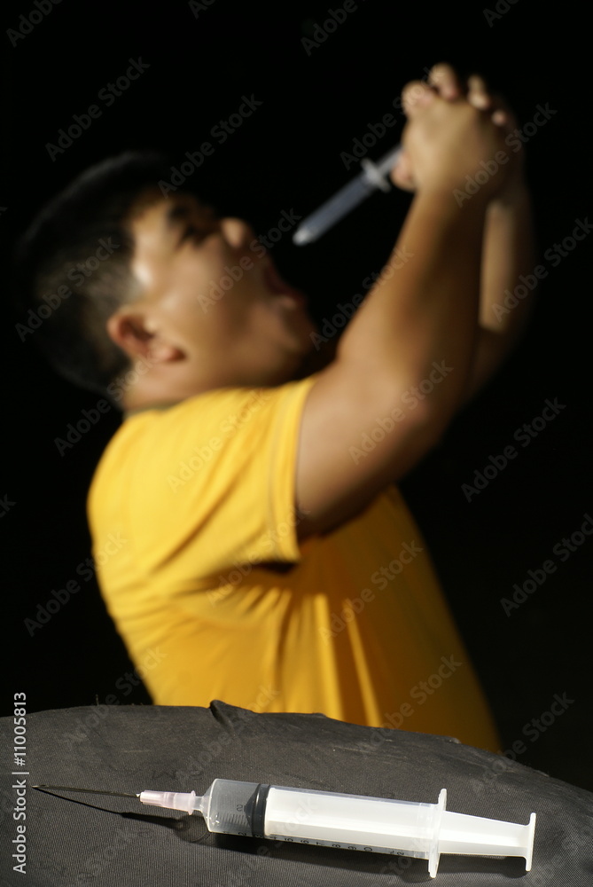 Asian man trying to eat syringe