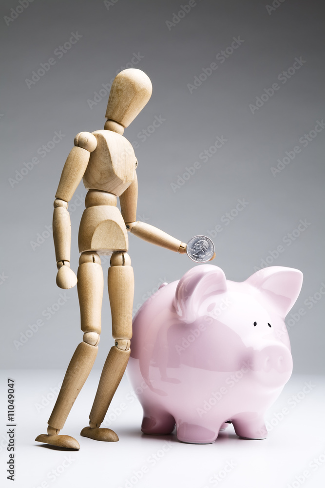 Manikin dropping a coin into a piggy bank Manikin dropping a coin into a piggy bank