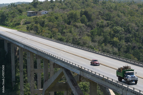 Bridge over green tropical forest with truck and car