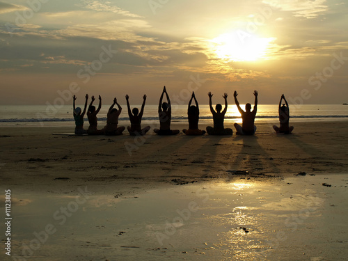 Yoga class at sunset by the ocean