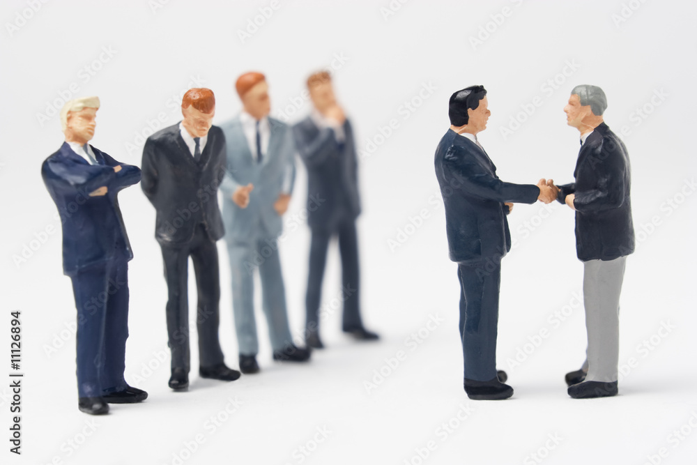 Two business figurines shaking hands Two business figurines shaking hands