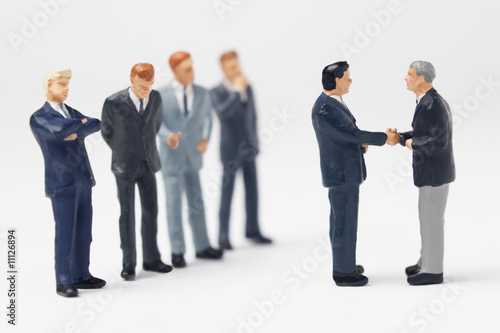 Two business figurines shaking hands