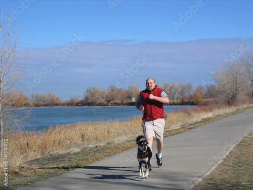 Man running with Dog next to lake