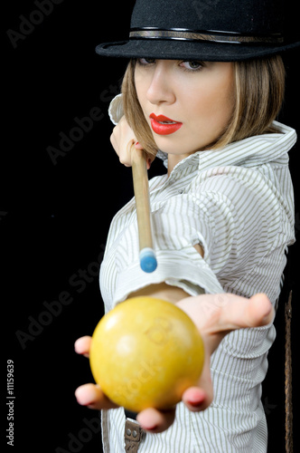 Pretty girl in hat with billiard cue and a ball