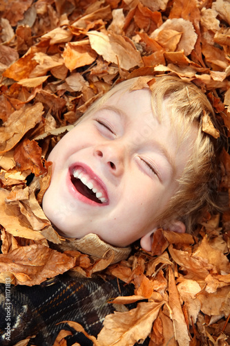 Laughing boy in a pile of leaves