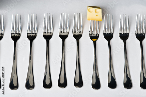 Row of metal forks with cheese