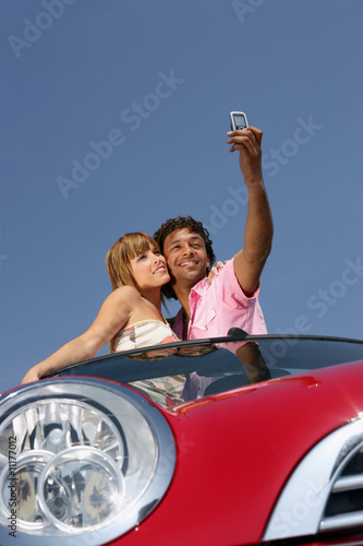 Couple se photographiant dans une voiture décapotable photo