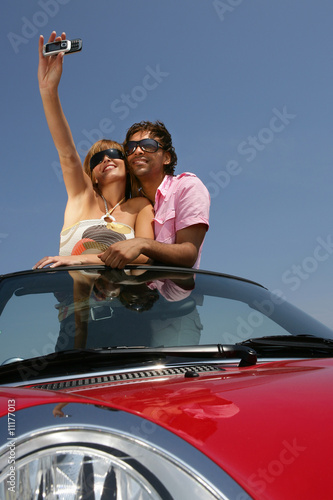 Jeune couple se prenant en photo dans voiture décapotable © auremar