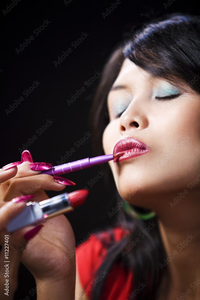 Young woman applying lipstick using brush Young woman applying lipstick using brush