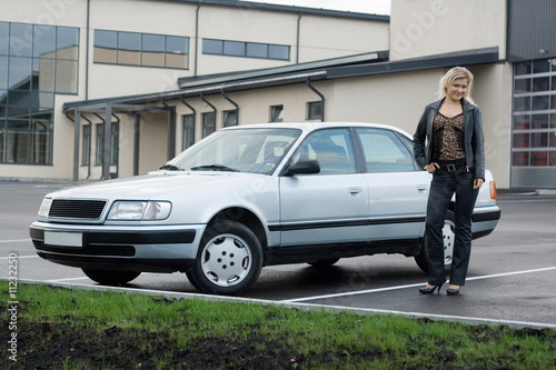 Blonde girl with a car at empty parking place. © Sergejs Nescereckis