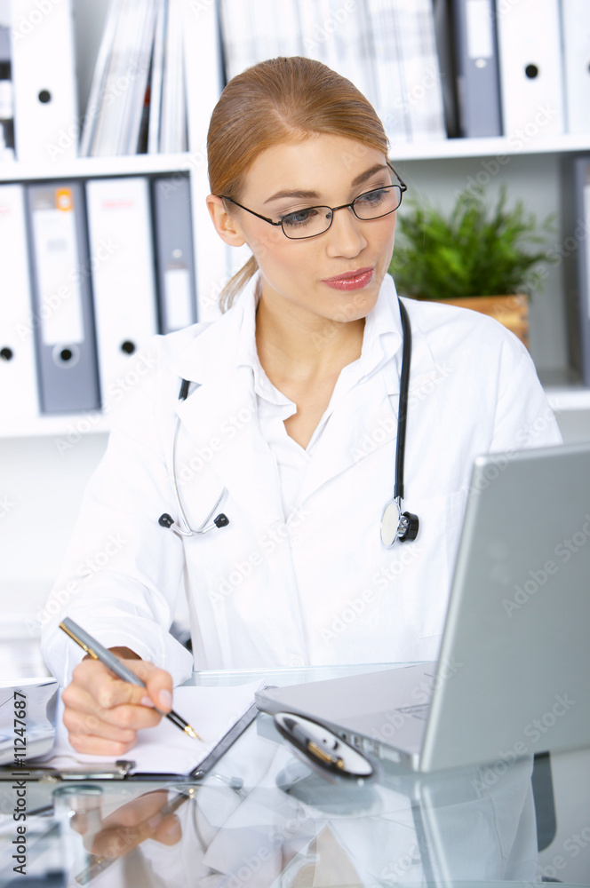 Smiling female doctor writing notes in clipboard Smiling female doctor writing notes in clipboard