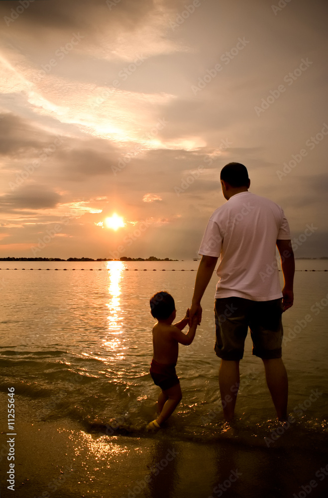 Father and son on the beach holding hands during sunset