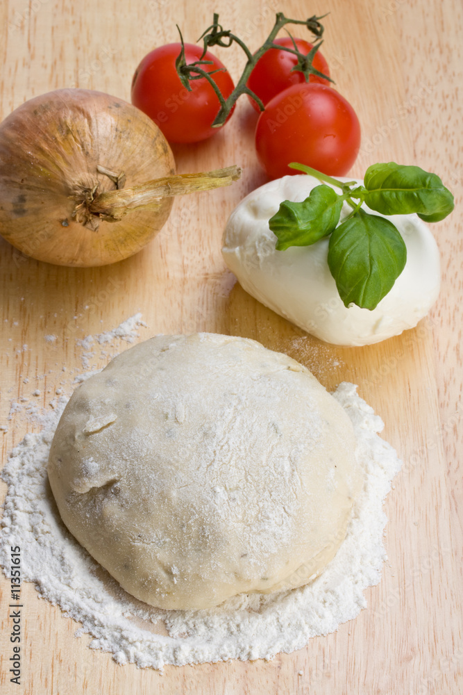 Hefeteig, Käse, Tomaten und Zwiebeln auf einem Holzbrett Hefeteig, Käse, Tomaten und Zwiebeln auf einem Holzbrett