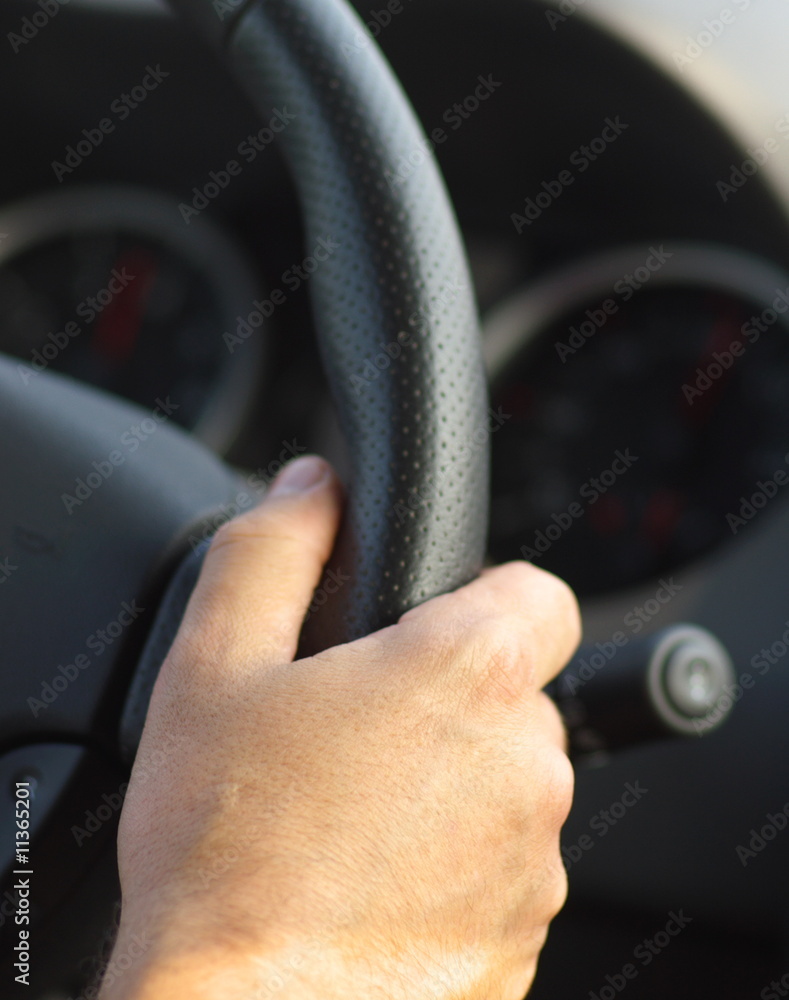 Man's hand on car steering close, black, vertical