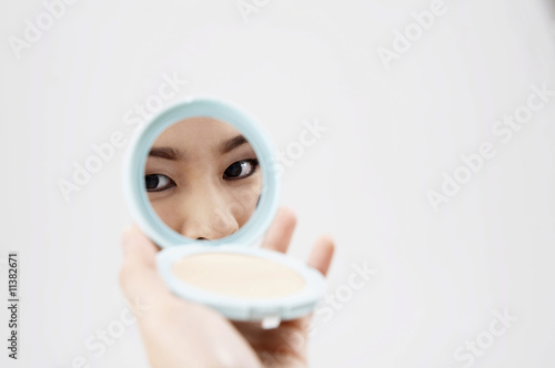 Woman looking in compact mirror photo