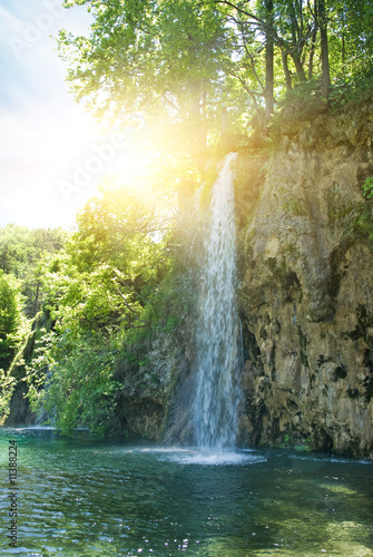 Sunrise over waterfall in wild forest © Nejron Photo