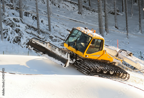Ski slope with a yellow ratrak doing track maintenance
