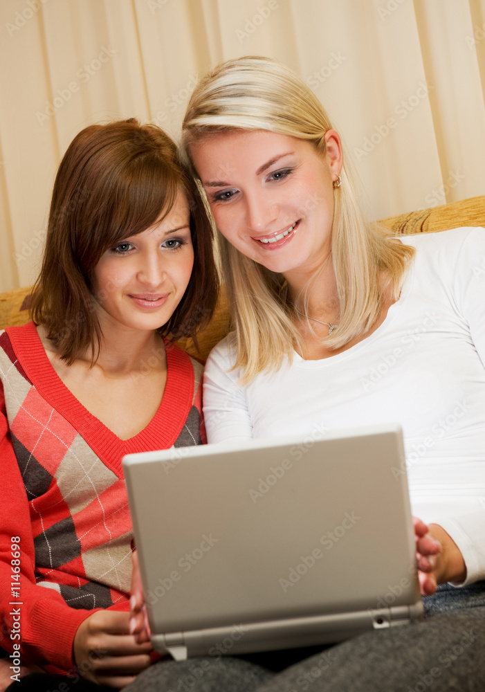 Two beautiful women having fun working with on laptop Two beautiful women having fun working with on laptop