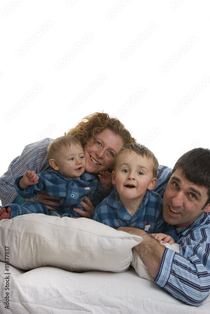 Family of four relaxes in bed