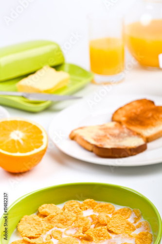 bowl of cornflakes with milk, toasts, orange and orange juice