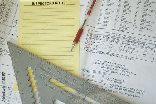 Inspection notes, ruler, and red pen atop construction plans