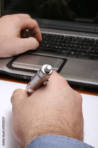 Homem a escrever com o computador na sua frente
