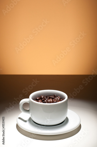 cup of coffee filled with coffee beans, orange background