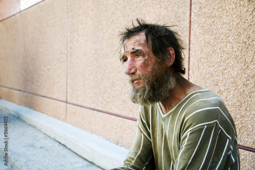 Sad homeless man on city street photo