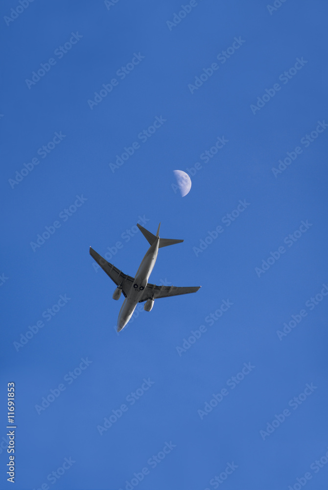 Fototapeta premium Ein Flugzeug im Flug von direkt unterhalb, mit Mond