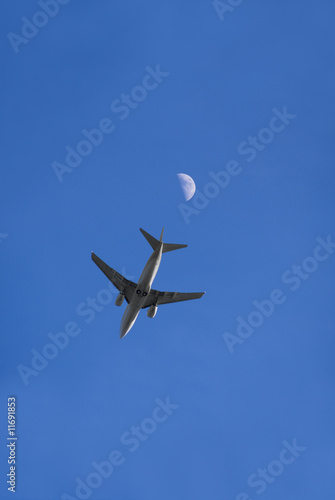 Ein Flugzeug im Flug von direkt unterhalb, mit Mond