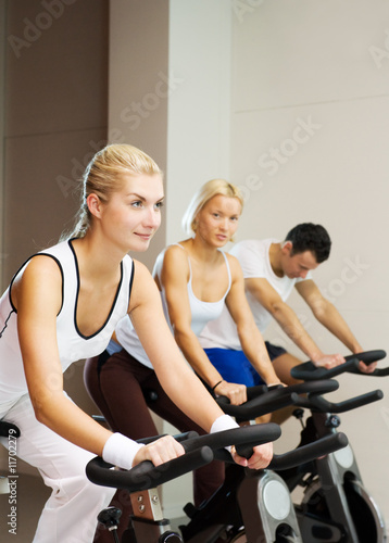 Fototapeta Naklejka Na Ścianę i Meble -  Group of people doing exercise on a bike in a gym