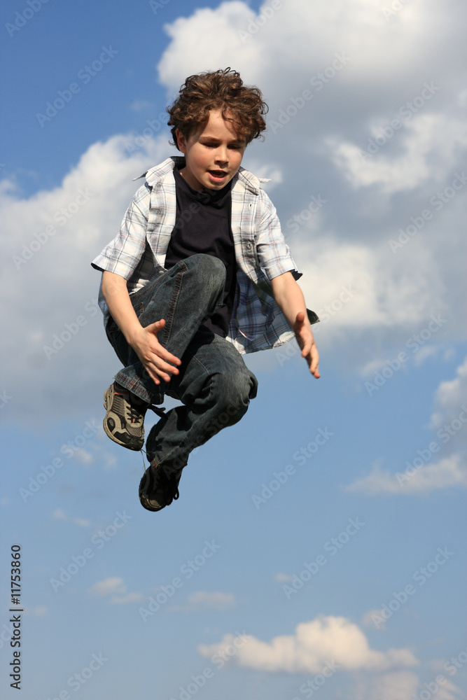 Kid running, jumping on green meadow against blue sky Kid running, jumping on green meadow against blue sky