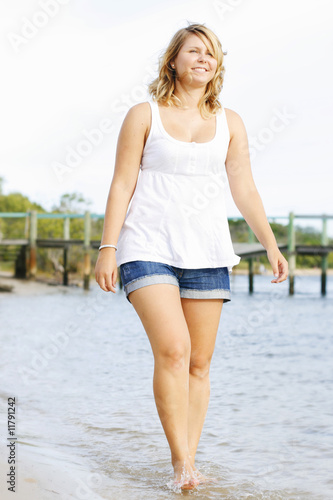 Beautiful young caucasian woman walking in water