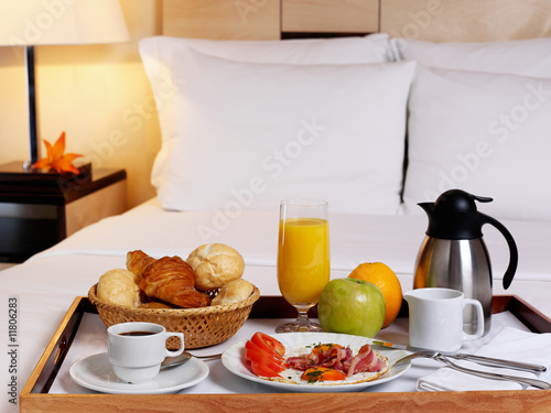 Tray with breakfast on a bed in a hotel room.