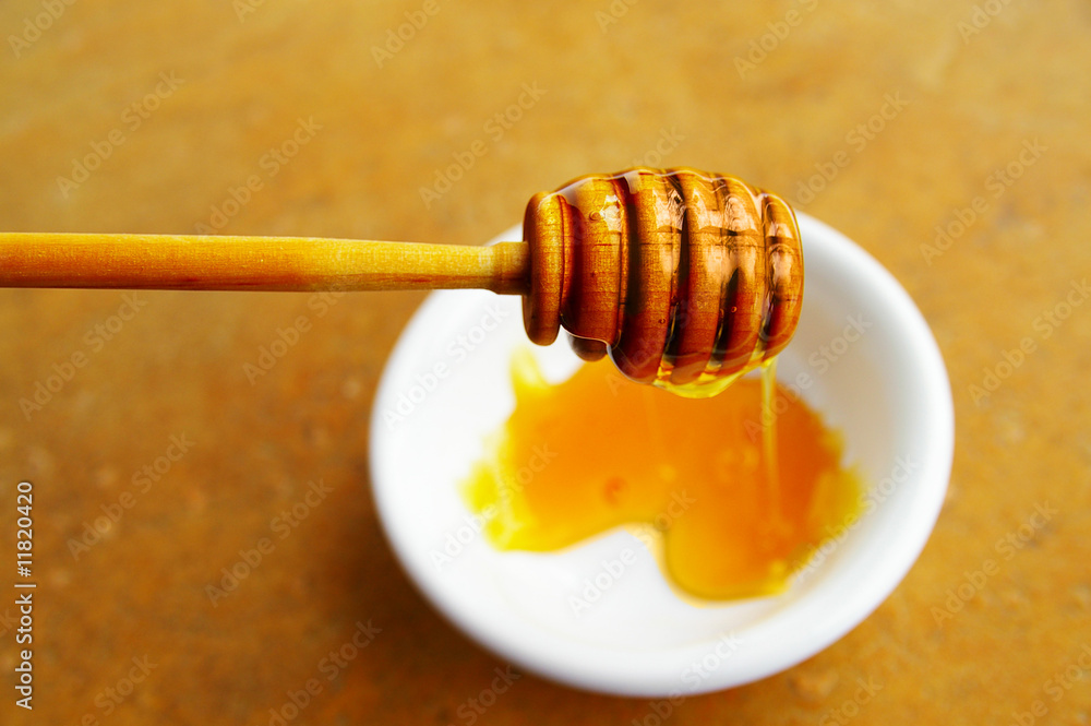 honey being dripped into a white bowl honey being dripped into a white bowl