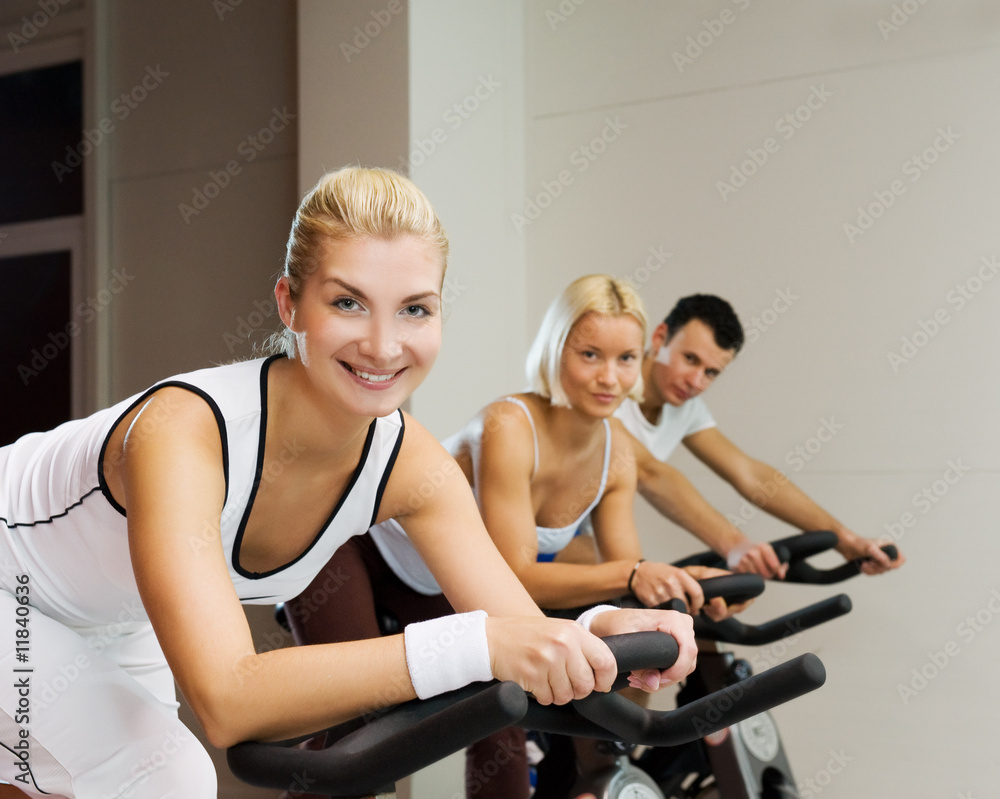 Group of people doing exercise on a bike in a gym Group of people doing exercise on a bike in a gym