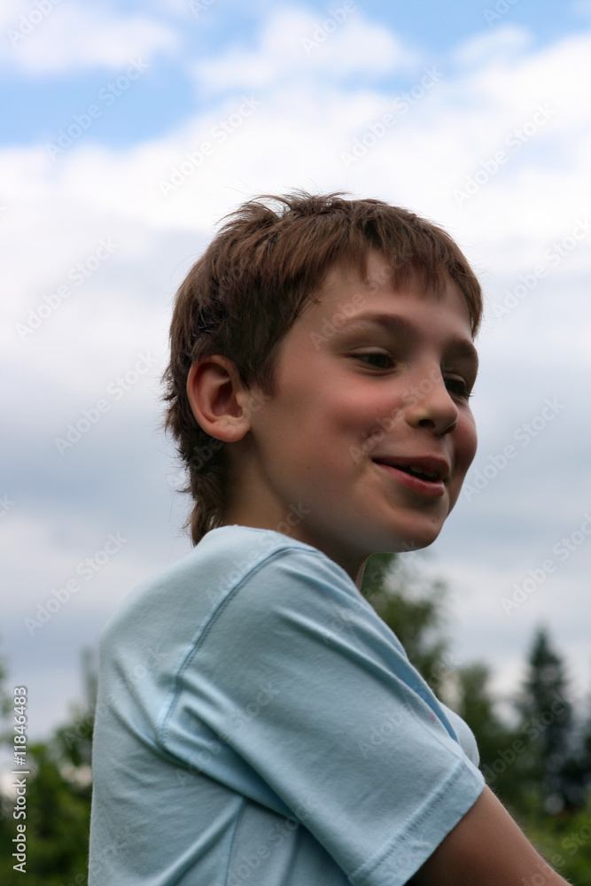 A smiling teenager half-turned on a background of clouds A smiling teenager half-turned on a background of clouds