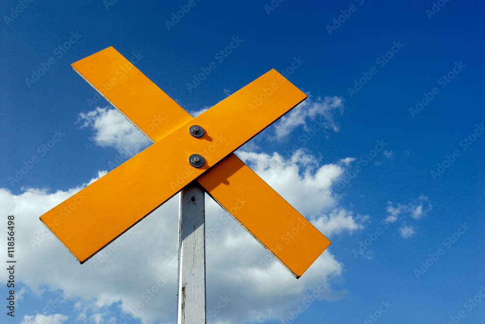 ein gelbes Kreuz vor blauem Himmel mit Wolke