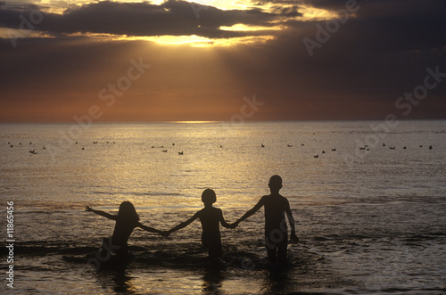 Silhouetted kids playing on the beach at sunset