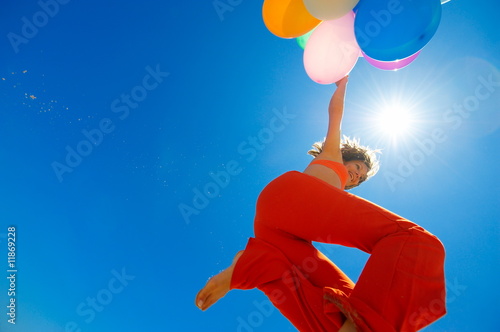 young woman with colorful balloons jumping